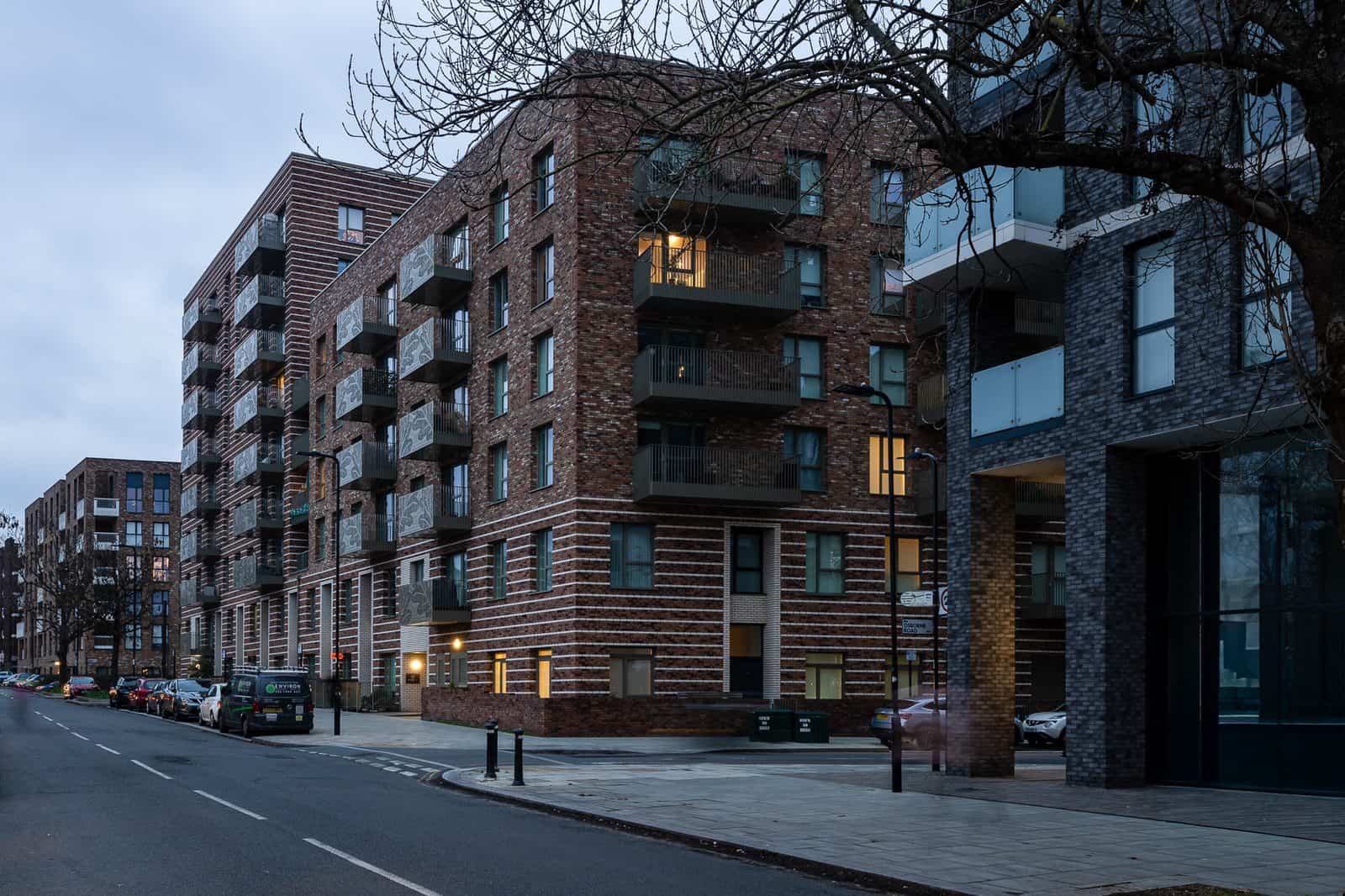 New-build London apartment buildings photographed at dusk with lit windows